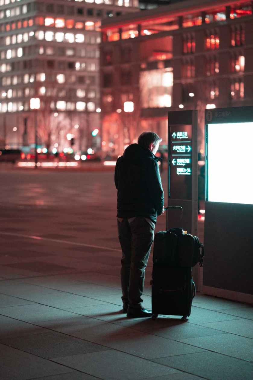 man standing beside black luggage on street